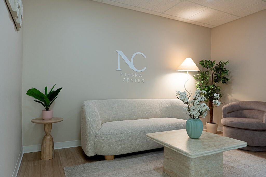 Calm waiting room at Niyama Center with a cream sofa and a plant